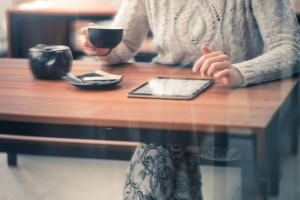 Donna con tablet e caffè. Inflazione e opinioni di CEO USA in background.