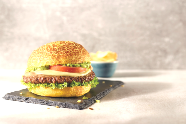 Hamburger gourmet Autogrill con carne, formaggio, pomodoro e insalata su tagliere in ardesia. Sosta di qualità.