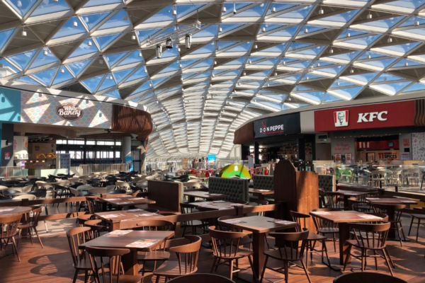 Interno ristorante travel retail: tavoli, sedie, vetrate. Ristorazione in aeroporto e centri commerciali.