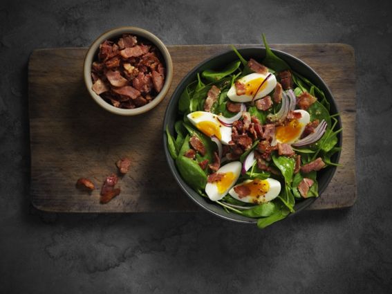 Insalata con bacon cotto Tulip Professional, uova e cipolla rossa. Bacon croccante in ciotola.
