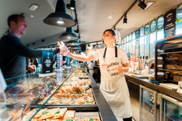 Autogrill: formazione del personale. Addetta serve pizza al cliente nel bistrot.