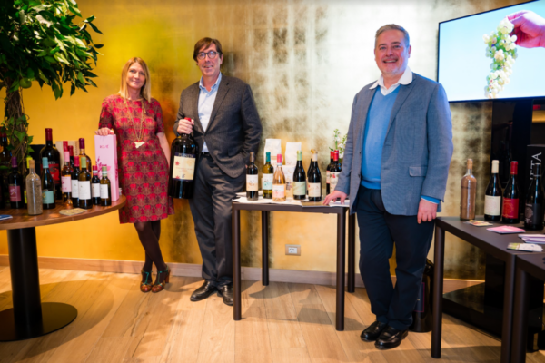 Presentazione vini Planeta all'aeroporto di Palermo. Persone con bottiglie di vino siciliano. Degustazione vini.