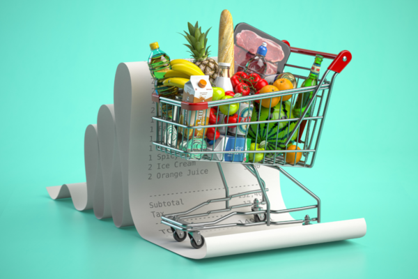 Carrello spesa pieno di alimentari con scontrino lungo. Spesa green e sostenibile.