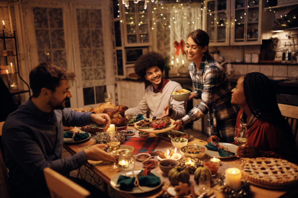 Cena festiva in famiglia. Persone a tavola con tacchino, candele e torta.