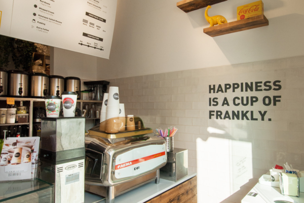 Interno di Frankly: macchina caffè Faema, tazze, scritta Happiness is a cup of Frankly. Arredamento moderno.