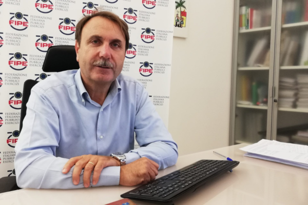 Fipe, caro bollette: Immagine di un uomo seduto alla scrivania.