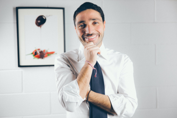 Ubri, sostenitore del Pos. Ritratto di uomo sorridente in camicia e cravatta, con quadro artistico sullo sfondo. Manovra economica.