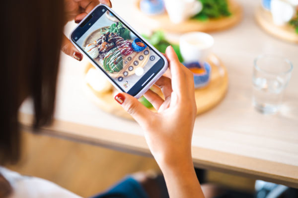 Foto di cibo al ristorante. Donna fotografa il pranzo con smartphone. Servizi di mensa.