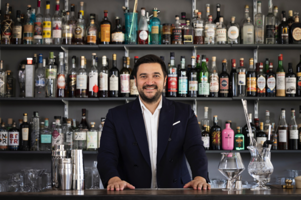 Barman esperto dietro il bancone. Trend mixology 2023, cocktail bar con bottiglie di liquori.