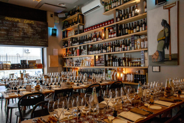 Interni di Roscioli Soho: tavoli apparecchiati, scaffali di vini e prodotti alimentari. Cucina italiana a New York.