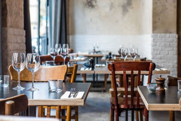 Interno ristorante TheFork: tavoli apparecchiati con bicchieri e posate. Ristorazione e inflazione nel 2023.