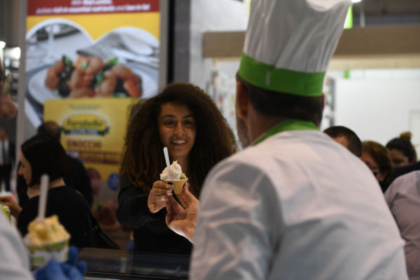 Cibus 2023: donna assaggia gelato artigianale. Fiera Horeca, food e fuori pasto.