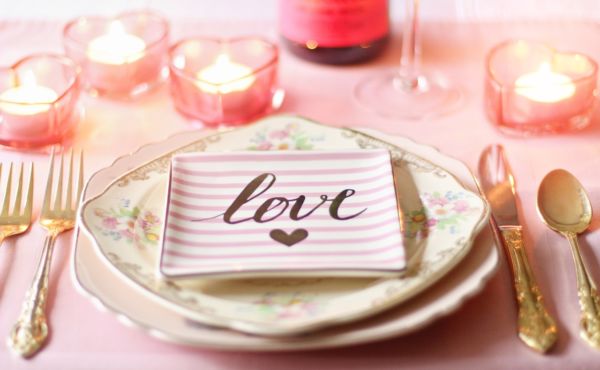 Tavola romantica San Valentino. Candele a cuore, piatto love. Cena romantica ristorante.