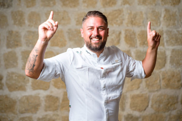 Diego Vitagliano, pizzaiolo napoletano, apre a Roma. Sorridente, indica il cielo.