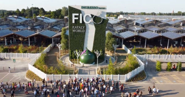 Ingresso FICO Eataly World Bologna. Facciata verde con scultura a forma di fico. Persone in primo piano.