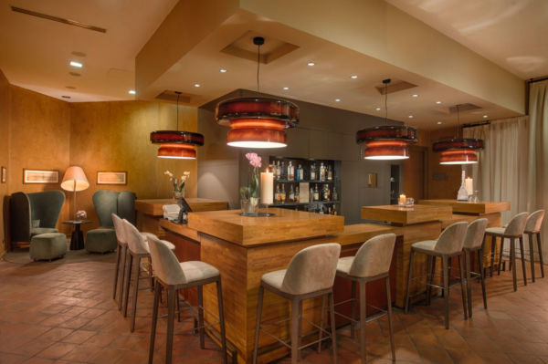 Bar La Pista Bistrot, Hotel NH Collection Torino Santo Stefano. Sedie, bancone in legno e luci soffuse.