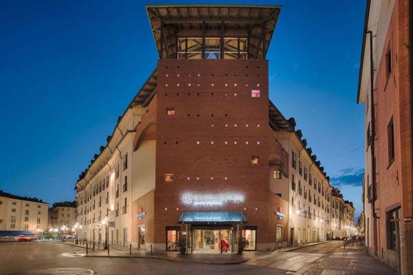 Facciata notturna dell'Hotel NH Collection Torino Santo Stefano con La Pista Bistrot di Gerla 1927.