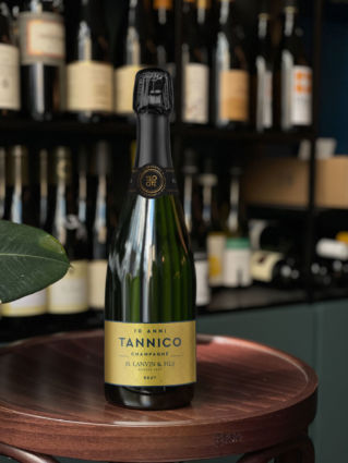 Bottiglia celebrativa Tannico 10 anni. Champagne H. Lanvin & Fils su tavolo in legno. Anniversario Tannico, vino di alta gamma.