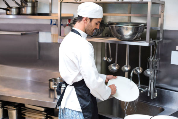 Chef lava piatti in ristorante. Risparmio idrico in cucina Horeca.