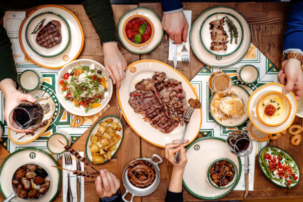 Tavola imbandita Il Mannarino: carne alla griglia, contorni e vino. Nuove aperture 2023.
