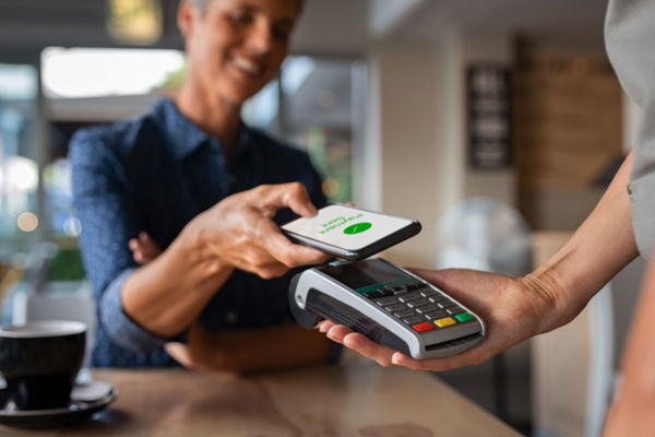 Donna paga con smartphone tramite POS. Commissioni POS e pagamenti digitali.