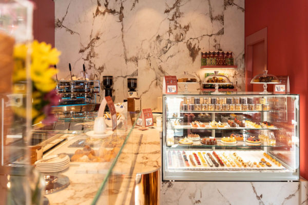 Interni della pasticceria Baunilla Brera. Vetrina dolci, banco in marmo, macchina caffè.