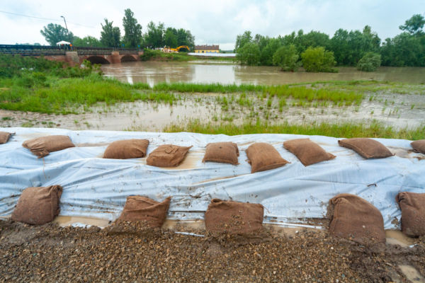Alluvione Emilia-Romagna: sacchi di sabbia contro l'acqua alta. Ponte sullo sfondo. Disastro ambientale 2023.