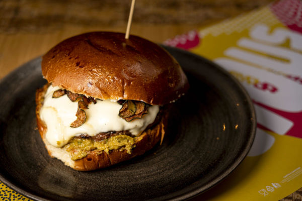Burger Golocious su piatto. Acquisizione Fedegroup, crescita estera. Panino gourmet con formaggio fuso.