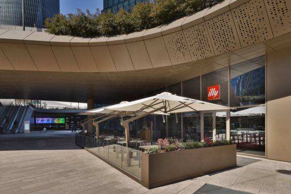 illy CityLife Milano: nuovo flagship store. Tavolini esterni con ombrelloni, design moderno.