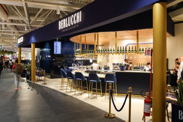 Bar Berlucchi Franciacorta a Fiumicino. Design elegante, sedute blu, bottiglie in esposizione. Autogrill food court.