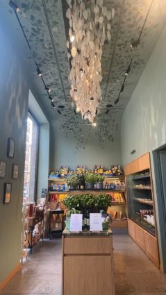Interni Pinzimonio: ortofrutta e cucina. Lampadario di design, scaffali con frutta fresca, ambiente curato.