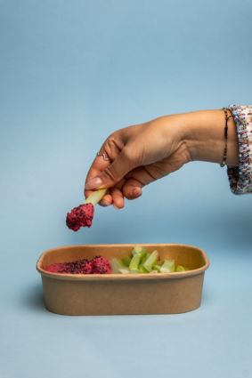 Pinzimonio: mano con sedano e salsa rosa. Ortofrutta fresca, cucina sana.