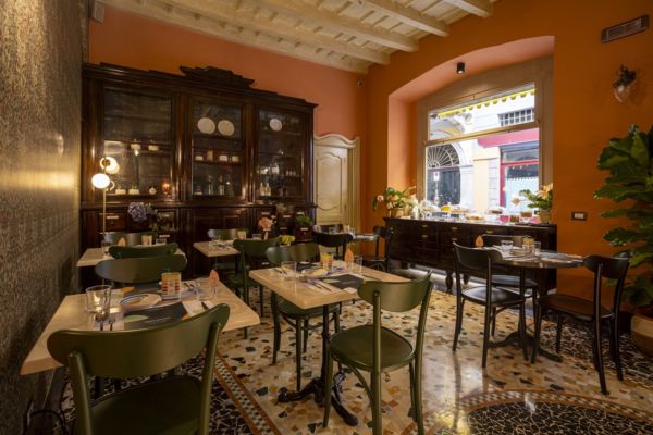 Interni del ristorante Mediterranea a Milano: tavoli apparecchiati, vetrina antica e pavimento decorato.