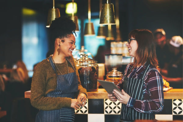 Personale sorridente usa tablet per programma fedeltà ristorante. Tecnologia e ristorazione.