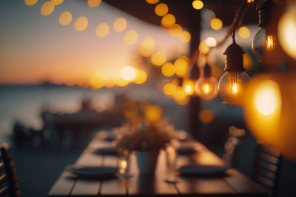 Bar ristorante sul mare al tramonto. Turismo sostenibile, atmosfera accogliente con luci soffuse.