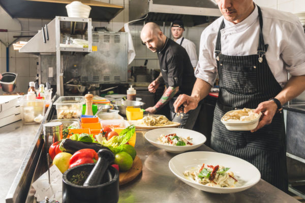 Cucina ristorante: chef preparano piatti di pasta. Ristorazione e Fipe.