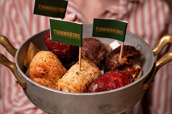 Assortimento di carne Il Mannarino in padella. Specialità gastronomiche e bandierine del brand.