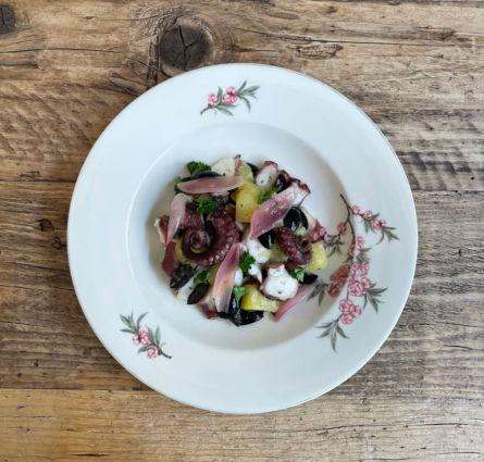 Insalata di polpo, patate e olive nere di Gelsomina. Piatto di portata decorato con fiori.