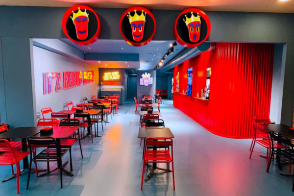 Interno di Kebhouze: tavoli e sedie rosse, bancone rosso, logo kebab con corona. Design moderno e vivace.