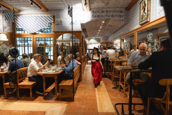 Interno della bierstube Löwengrube Milano. Persone sedute ai tavoli, cameriera in abito tradizionale.