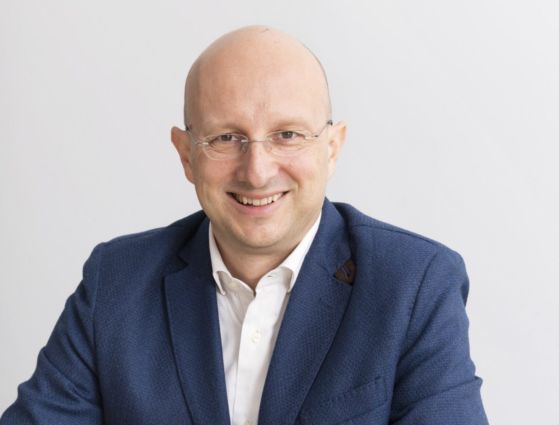 Uomo sorridente in giacca, settore Horeca. Fatturati in crescita nel 2023.