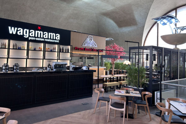 Interni del ristorante Wagamama a Roma Termini, con bar e tavoli. Cucina pan-asiatica.