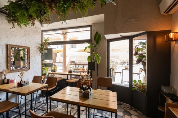 Interni accoglienti del Corner Bar: tavoli in legno, sedie in pelle, piante e atmosfera rilassante. Caffè, stuzzicheria e bistrò.