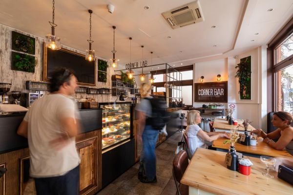 Interni accoglienti del Corner Bar Saragozza: caffè, stuzzicheria, bistrò e cocktail bar. Persone sedute ai tavoli.