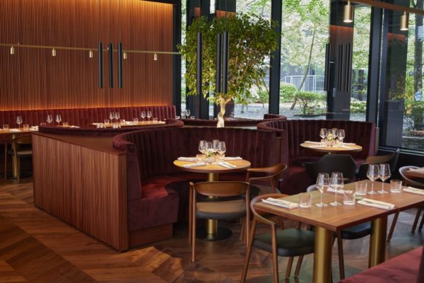 Interno del ristorante Cocciuto Turati a Milano. Arredamento elegante, divanetti in velluto bordeaux e tavoli apparecchiati.