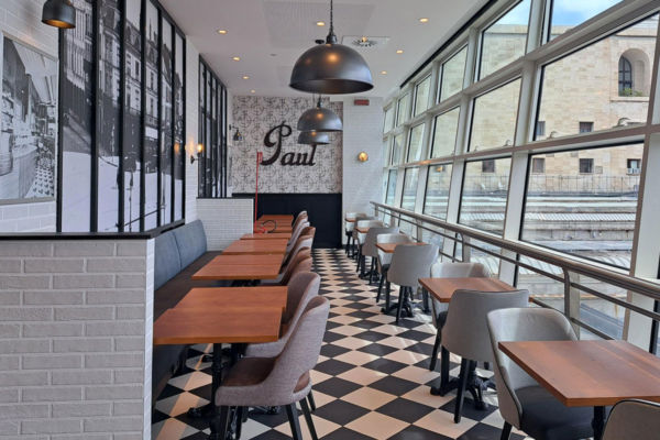 Interno del locale Paul a Roma Termini: tavoli, sedie e vista sulla stazione.