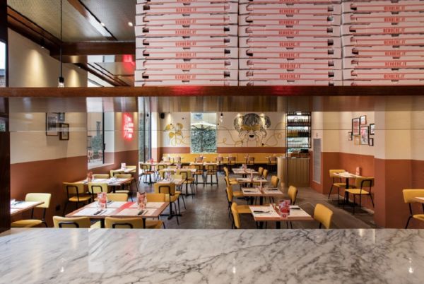 Interni Berberè: ristorante pizzeria con tavoli apparecchiati e pile di scatole pizza.