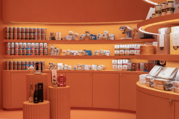 Interni di Incantalia, store a Trieste. Scaffali con caffè, tè, tazze e prodotti alimentari. Design arancione.