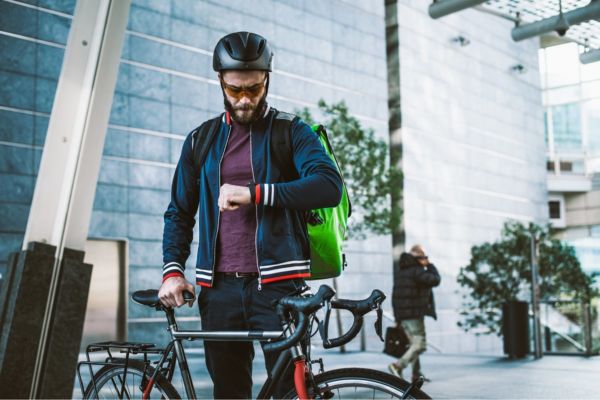 Ciclista delivery controlla l'ora. Piattaforme delivery contro New York City.