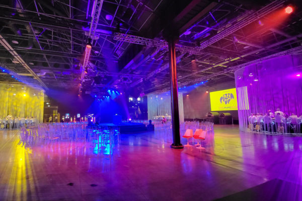 Sala eventi PizzaUp 2023: palco illuminato, sedie trasparenti, atmosfera vivace. #PizzaUp #Eventi #Pizza